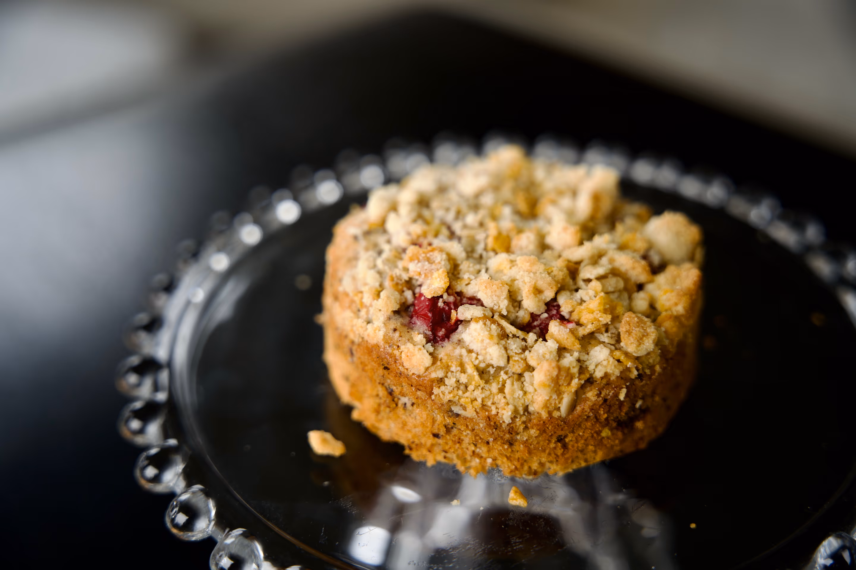 A berry crumble cake with oat streusel topping on a glass plate